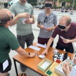 Slika prikazuje mlade obiskovalce Ovirantlona, ki se s prevezami za oči preizkušajo v igranju taktilnih UNO kart. Zelo so se zabavali!