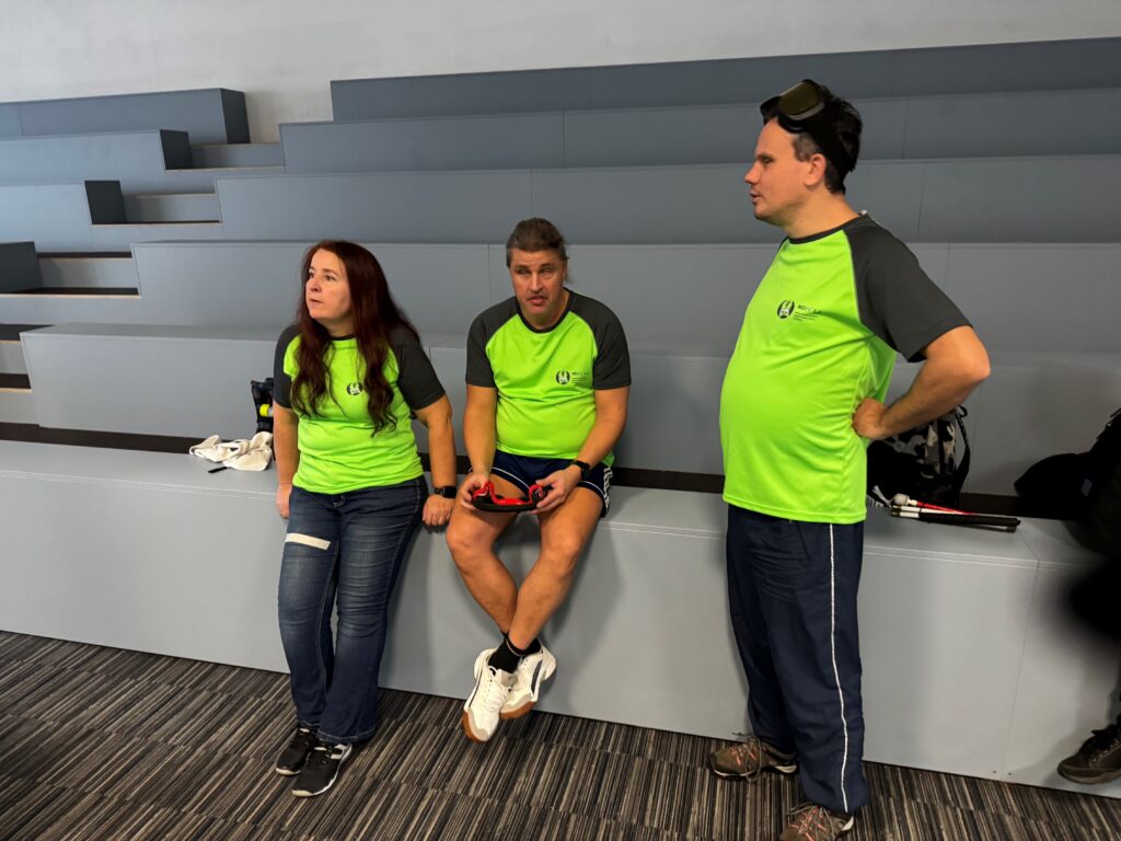 Slika prikazuje člana Mitjo Osolnika in Roka Janežiča ter spremljevalko, kako spremljajo tekmovanje.