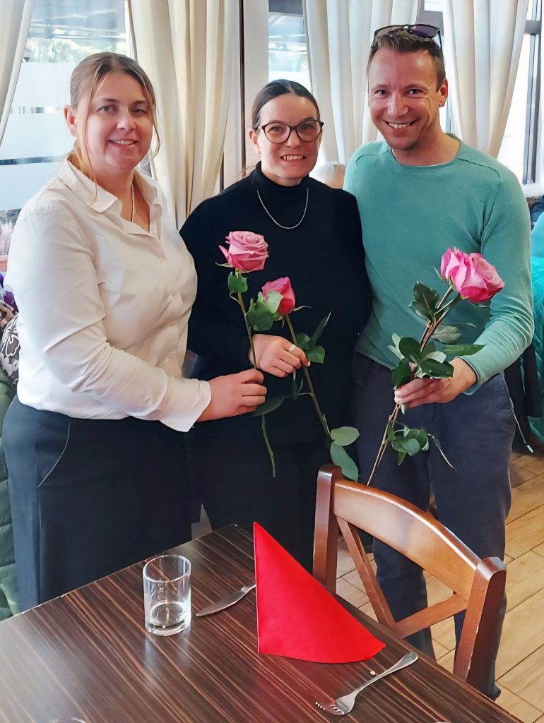 Tina Ušeničnik, predsednica, Branka Zorko predstavnica Zasavja v IO društva in Miha Belca, sodelavec strokovne službe društva za dostopnost. Zbrani stoje za omizjem, med srečanjem članstva iz Zasavja, v Trbovljah.