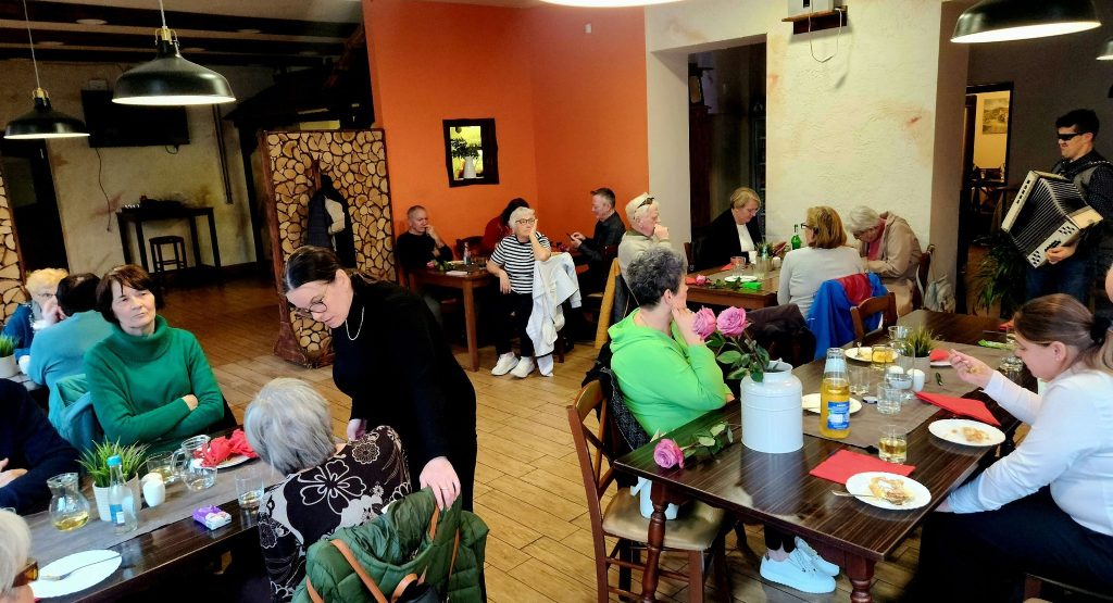 Članice in člani društva, zbrani za omizjem, med družabnim programom (pel in igral nam je Benjamin Škrab), na srečanju članstva iz Zasavja, v Trbovljah.